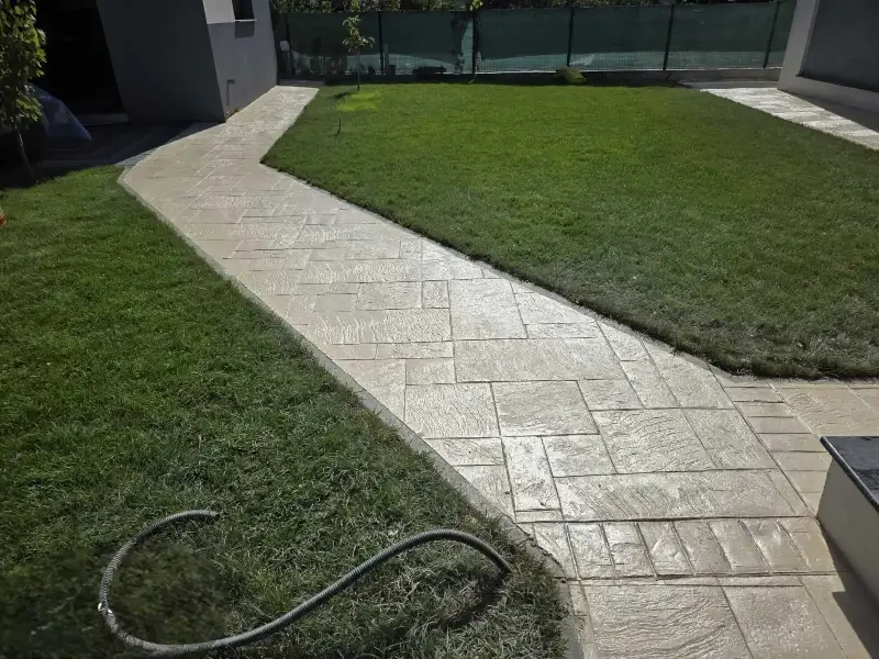 Alee de grădină din beton amprentat bej cu traseu elegant prin gazon realizată de RBETON