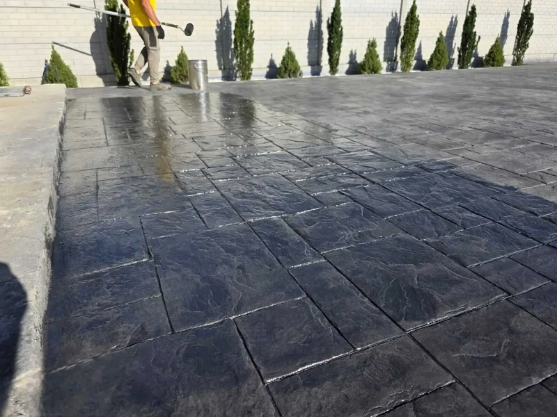 Curte mare cu beton amprentat negru grafit în proces de sigilare realizată de RBETON.
